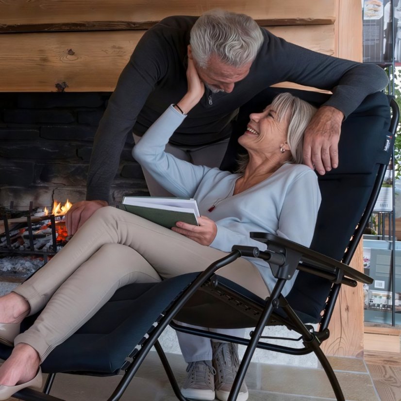 Relaxační křeslo Lafuma FUTURA AirComfort černá Acier v zimním interiéru, pohodová atmosféra s krbem.