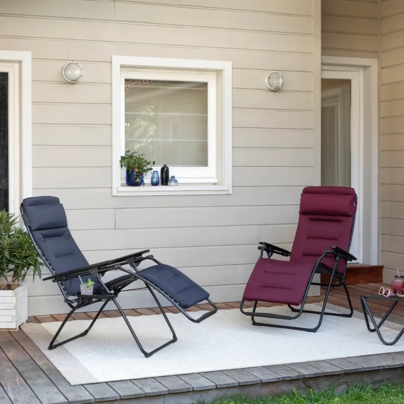 Relaxační křesla Lafuma FUTURA AirComfort červená a černá na zahradě při západu slunce.